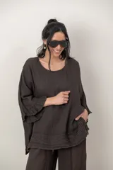 Blusa de lino color verde militar, holgada, de manga 3/4 con volados en los puños, cuello redondo y detalle de alforzas horizontales en el dobladillo.