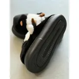 Pantuflas de peluche con diseño de vaca, confeccionadas en piel sintética suave. Cuentan con suela de goma antideslizante y diseño abierto en el talón.