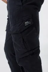 Pantalón cargo negro de sarga de algodón con spandex, con bolsillos laterales con solapa y etiqueta con el logo de la marca en uno de ellos.