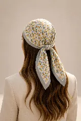 Pañuelo cuadrado con estampado floral en tonos amarillos y azules sobre fondo blanco, con borde liso en color celeste.