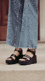Sandalia de cuero marrón con plataforma corrida y taco alto texturizado. Posee tiras delanteras múltiples y una pulsera al tobillo con hebilla ajustable.