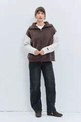 Cardigan de punto con diseño bicolor, cuerpo en color marrón y mangas largas en color crema con textura trenzada. Presenta cuello polo, cierre frontal con cremallera y puños acanalados.