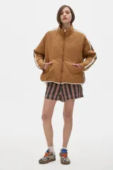 Campera marrón claro con diseño acolchado de rombos, cuello alto, cierre frontal con cremallera, bolsillos laterales y mangas largas con rayas blancas.