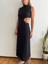 Vestido largo negro con cuello alto y aberturas laterales en la cintura.