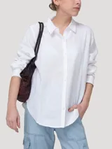 Blusa de lino orgánico color blanco, con cuello camisero, cierre frontal con botones y mangas largas.