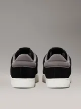 Zapatillas urbanas Calvin Klein Jeans de ante negro con logo CK grabado en el lateral, detalle de talón en gris, cordones grises y suela cupsole blanca.