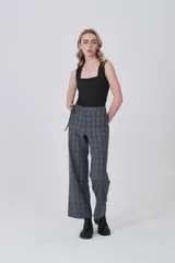 Pantalón de poliéster con estampado tartán en tonos grises y azules. Diseño de tiro medio, corte recto y ancho, con detalle de lazo ajustable en la cintura.
