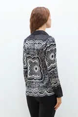 Camisa negra con estampado de arabescos en blanco y gris, de manga larga y corte clásico.