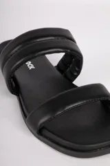 Sandalias bajas negras de símil cuero con dos tiras acolchonadas.