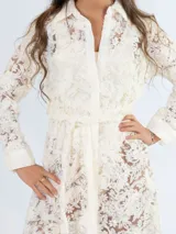 Vestido midi de encaje color crudo, con corte recto, cuello camisero y mangas largas. Incluye cinto de lazo en la cintura y cierre frontal con botones.