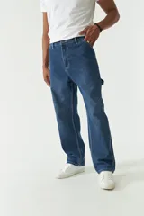 Jean estilo carpenter de corte relajado, recto y amplio, con diseño de cinco bolsillos y costuras reforzadas características del modelo. Presenta un acabado lavado en tono gris oscuro.