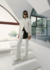 Pantalón sastrero de tiro bajo y diseño largo con botamanga acampanada, color blanco, con trabillas y cierre oculto.