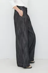 Pantalón de jean azul oscuro de tiro alto, con diseño holgado de pierna ancha, pinzas en la cintura y costuras a la vista.