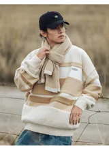 Buzo de tejido de punto con cuello redondo, manga larga y diseño de franjas horizontales en tonos beige, crema y marrón. Presenta textura en relieve en las franjas y un pequeño parche rectangular en el pecho.