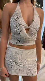 Top halter crop blanco con escote pronunciado y bordado de lentejuelas plateadas.
