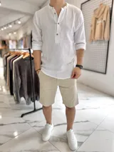 Camisa de muselina blanca de manga larga, con cuello mao y cierre frontal de botones.