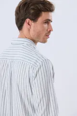 Camisa de manga larga de lino y algodón, con diseño de rayas verticales en tonos celestes y blancos. Presenta cuello camisero, cierre frontal con botones y pequeño bordado al tono en el pecho.