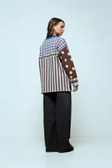 Sweater de punto con diseño geométrico y a rayas, de corte holgado y manga larga. Presenta un patrón combinado de lunares en las mangas, rombos en la parte superior y rayas verticales en el cuerpo.