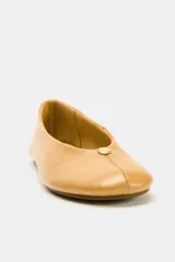 Zapato tipo bailarina plana de piel en color tostado, con pespuntes en el cuerpo, detalle metálico en la parte delantera y acabado en punta redonda.