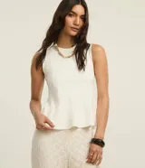 Blusa peplum sin mangas de color blanco, confeccionada en punto roma, con cuello redondo y diseño estructurado.