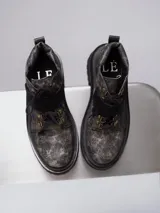 Borcego de punta redonda con efecto cuero desgastado, cordones y tira de velcro frontal. Cuenta con suela track y herrajes metálicos.