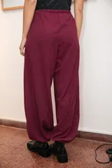 Pantalón tipo babucha de silueta relajada, color bordo, con cintura elástica ajustable mediante cordón y elásticos en los tobillos que generan un efecto abuchonado. Confeccionado en tela suave con acabado tipo piel de durazno.