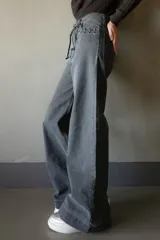 Jean de pierna ancha color gris oscuro, con cintura alta, bolsillos delanteros y traseros con detalle de trenzado, y cinturón de soga.