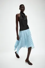 Falda midi de tiro medio color celeste con estampado de lunares negros, diseño asimétrico y forro interior. Cuenta con cierre lateral de cremallera oculta.