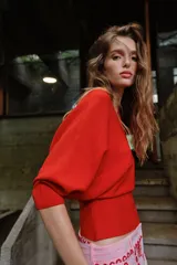 Jersey rojo de punto con escote en V pronunciado tanto en el delantero como en la espalda, mangas largas y diseño entallado en la cintura con caída acampanada.
