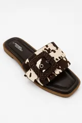 Sandalias planas de color beige claro con capellada ancha y hebilla cuadrada decorativa forrada en material trenzado.