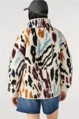 Campera bomber reversible con un lado de corderito estampado con manchas abstractas en tonos negro, marrón, azul y violeta sobre fondo blanco, y del otro lado liso en tono crudo.