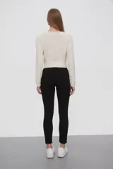 Pantalon de jean negro, corte skinny y tiro medio, con cierre frontal y bolsillos laterales.