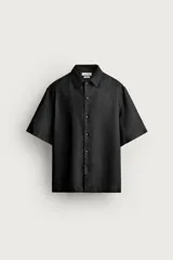 Camisa negra de manga corta, confeccionada en lino con corte relaxed fit, cuello bowling y cierre frontal de botonadura.