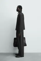 Sobrecamisa relaxed fit de Zara confeccionada en tejido negro con estructura diagonal. Presenta cuello subido, manga larga, bolsillos de vivo en la cadera y cierre frontal con cremallera.