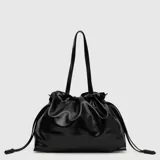 Cartera tipo shopper de cuero vegano brillante, con diseño fruncido en la parte superior mediante cordones laterales ajustables. Cuenta con doble asa larga para llevar al hombro y logo de la marca en la parte frontal.