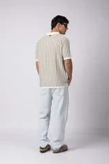 Chomba de tejido de punto con diseño de rayas verticales en tonos beige y marrón, cuello polo y mangas cortas con terminación acanalada.