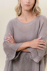 Buzo de tejido liviano con brillo sutil tipo lurex, color beige o dorado claro. Presenta un calce suelto (oversize) con mangas amplias y cuello redondo. El ruedo tiene un detalle de terminación festoneado con pequeños calados.