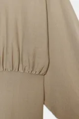 Cuerpo de punto con cuello redondo y mangas largas abullonadas. Presenta un diseño con cintura entallada y bajo ajustado.