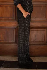 Conjunto de dos piezas compuesto por camisa de manga larga con botones frontales y pantalón de corte recto, ambos en color negro con estampado de pequeños puntos brillantes tipo strass.