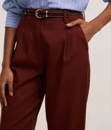 Pantalón carrot de cintura alta y corte zanahoria, color bordó, confeccionado en viscolino con pliegues en el frente y trabillas. Incluye cinturón fino de poliuretano con hebilla.