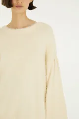Sweater de tejido de punto con acabado afelpado, cuello redondo y mangas largas de volumen amplio. Diseño liso en color beige con silueta relajada.