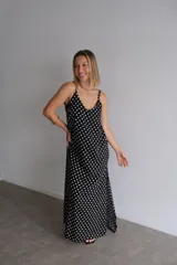Vestido largo de crepe con estampado de lunares negros sobre fondo blanco. Presenta un diseño de corte holgado con breteles finos y escote redondeado.