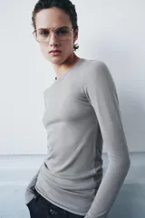 Jersey de punto fino color naranja, con cuello redondo y manga larga.