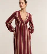 Vestido largo evasé de Marfinno, confeccionado en mezcla de viscosa y lino, con diseño de rayas verticales en tonos bordó y beige. Presenta escote en V, busto ajustado y mangas largas abullonadas con puños elastizados.