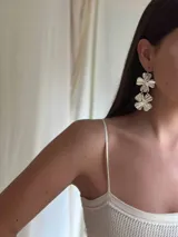 Aros colgantes plateados con dos dijes en forma de flor texturadas.