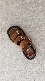 Sandalias de cuero negro con punta semicuadrada, taco cuadrado bajo y tres tiras frontales con hebillas metálicas plateadas. Cuentan con tira trasera con cierre ajustable.