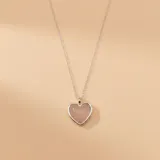 Collar de cadena fina de plata con un dije en forma de corazón que contiene una piedra de cuarzo rosa engarzada.