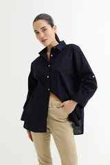 Camisa color crudo, de corte clásico, con cuello camisero, cierre frontal con botones y mangas 3/4 con trabillas.