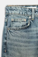 Jeans de tiro alto con cinco bolsillos, trabillas para cinturón y cierre frontal con cremallera y botón metálico. Presenta un lavado desteñido en la zona frontal y un corte recto ligeramente ajustado en los tobillos.