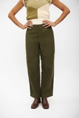 Pantalon de corte recto y tiro alto en color verde oliva, confeccionado en tejido con textura similar a la gamuza. Presenta costuras horizontales a la altura de las rodillas y cierre frontal con botón oculto.